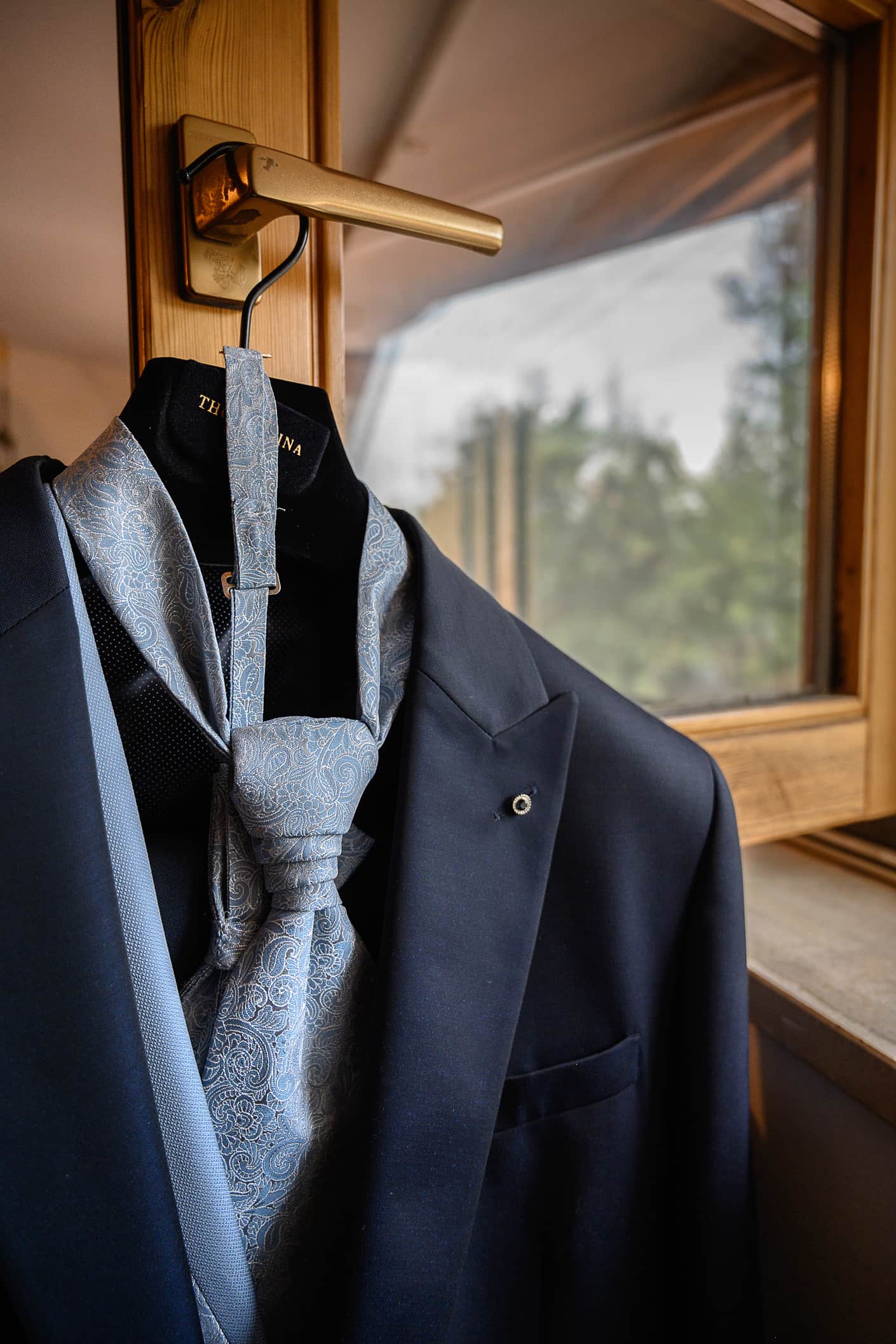 giacca e cravatta dello sposo appesi alla finestra della cameretta